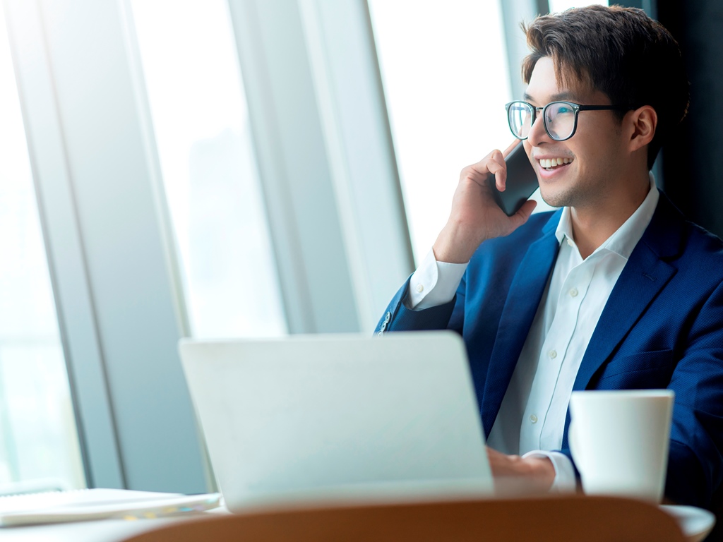 creative agency smart glasses asian male formal cloth conversation with smartphone freelance working with laptop at coworking area office space with freshness with blur office background